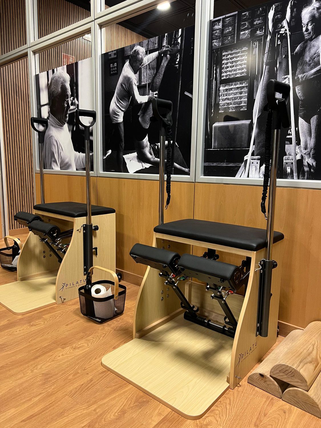 Cadillac y wunda chair de madera junto a fotos antiguas de Joseph Pilates